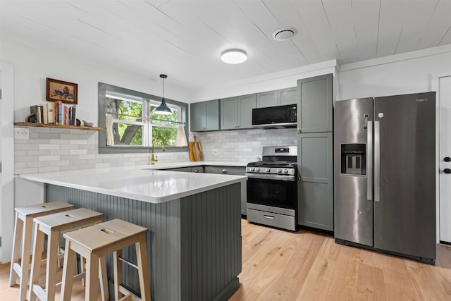 7516 Deaver Dr, North Richland Hills, TX 76180 - kitchen featuring stainless steel appliances, a peninsula, backsplash, light wood-type flooring, and a kitchen breakfast bar