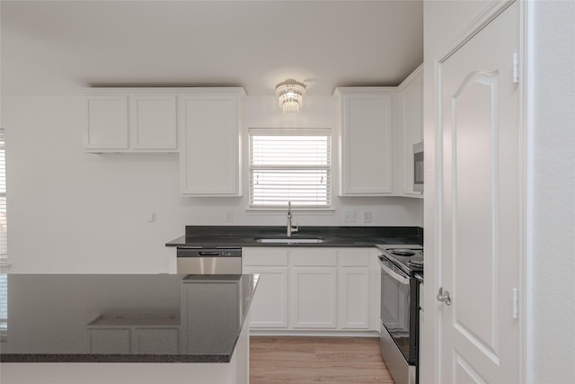 2912 Lighthouse Dr, Denton, TX 76210 - kitchen featuring appliances with stainless steel finishes, dark countertops, white cabinetry, and light wood-type flooring