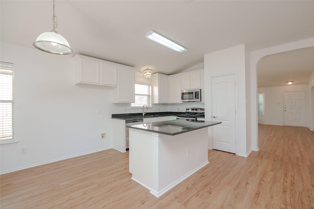 2912 Lighthouse Dr, Denton, TX 76210 - kitchen with stainless steel appliances, arched walkways, dark countertops, light wood-style flooring, and lofted ceiling
