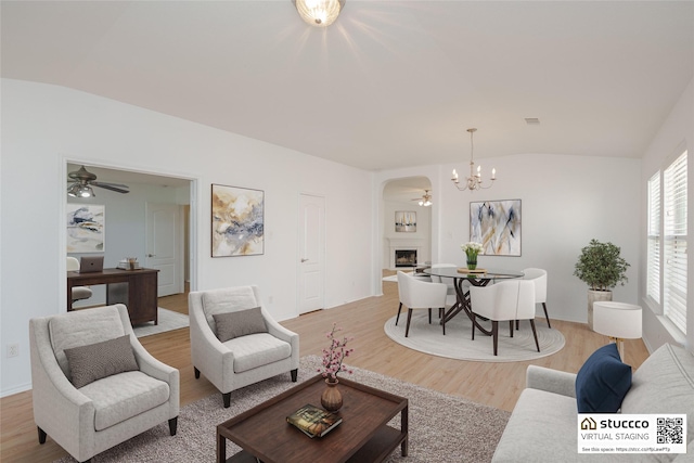 2912 Lighthouse Dr, Denton, TX 76210 - living area featuring vaulted ceiling, a ceiling fan, light wood-type flooring, a fireplace, and a chandelier