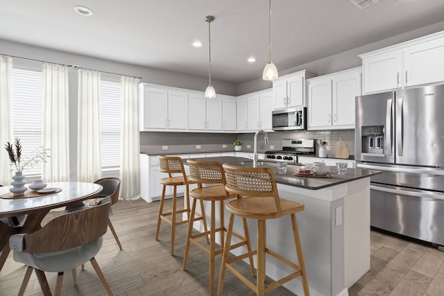 724 Cromane Rd, Fort Worth, TX 76052 - kitchen with stainless steel appliances, dark countertops, decorative backsplash, light wood finished floors, and a kitchen island with sink