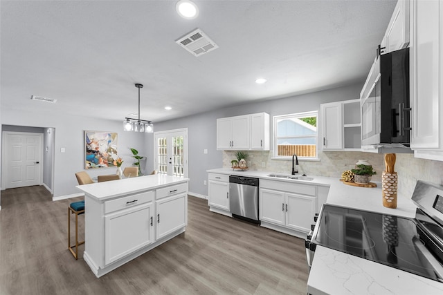 2473 W Five Mile Pkwy, Dallas, TX 75233 - kitchen with stainless steel appliances, decorative backsplash, recessed lighting, a center island, and light wood-type flooring