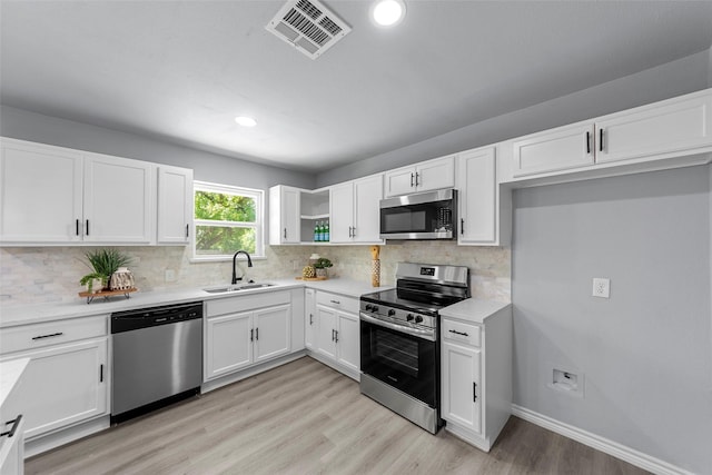 2473 W Five Mile Pkwy, Dallas, TX 75233 - kitchen with appliances with stainless steel finishes, light wood finished floors, white cabinets, decorative backsplash, and recessed lighting