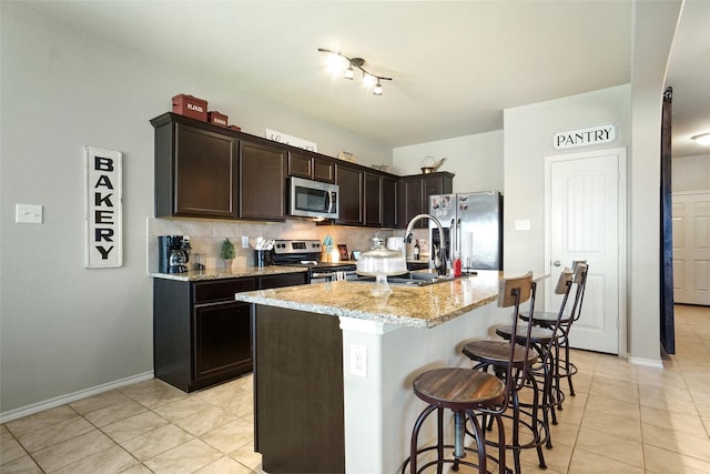 322 Chestnut Ln, Ponder, TX 76259 - kitchen with stainless steel appliances, light tile patterned flooring, a breakfast bar area, light stone counters, and dark brown cabinets