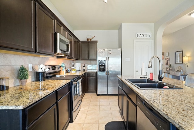 322 Chestnut Ln, Ponder, TX 76259 - kitchen with stainless steel appliances, arched walkways, dark brown cabinets, and light stone countertops