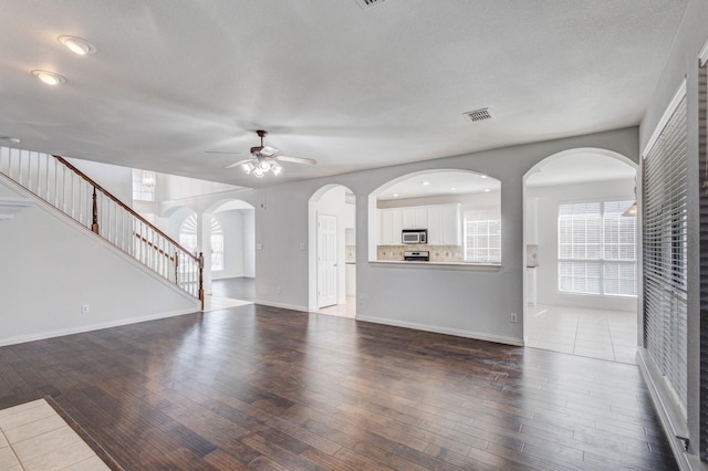 7101 Bickers Dr, Rowlett, TX 75089 - unfurnished living room featuring ceiling fan, hardwood / wood-style flooring, stairway, and arched walkways