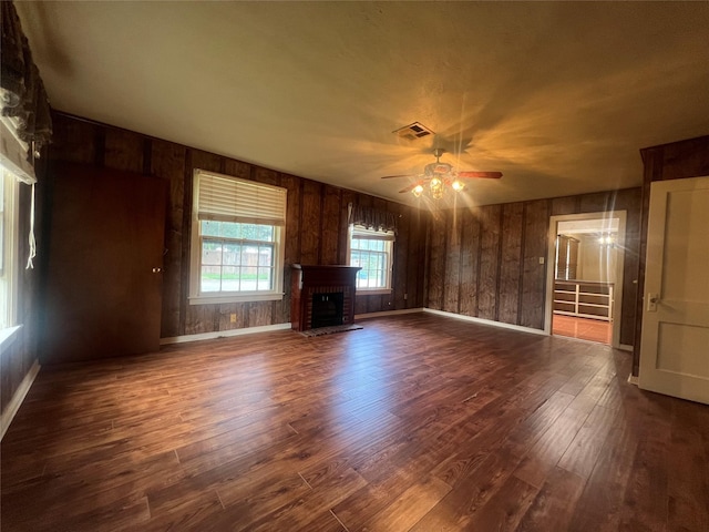 717 N 37th St, Corsicana, TX 75110 - unfurnished living room featuring a ceiling fan, a fireplace, wood finished floors, and wood walls