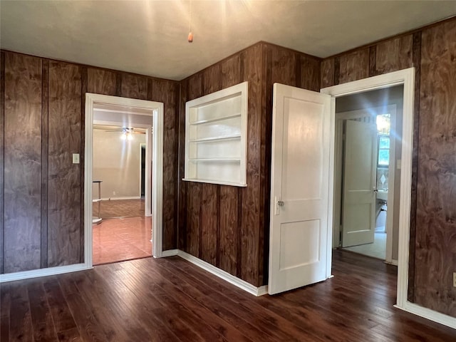 717 N 37th St, Corsicana, TX 75110 - unfurnished bedroom featuring dark wood-type flooring, wooden walls, and ensuite bathroom