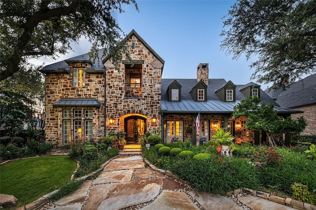 5332 Longvue Dr, Frisco, TX 75034 - view of front of home with a standing seam roof, french doors, stone siding, a chimney, and a metal roof