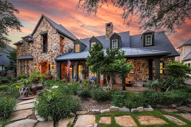 5332 Longvue Dr, Frisco, TX 75034 - view of front of house with a standing seam roof, stone siding, a chimney, a metal roof, and roof with shingles