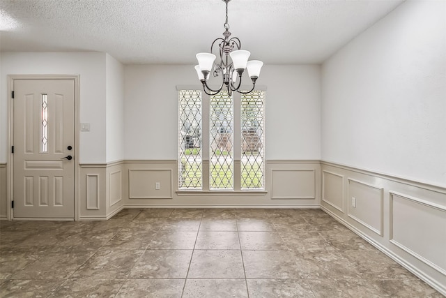 2526 Axminster Dr, Grand Prairie, TX 75050 - unfurnished dining area featuring a wainscoted wall, a chandelier, a textured ceiling, and a decorative wall