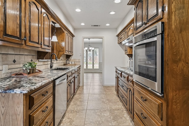 2526 Axminster Dr, Grand Prairie, TX 75050 - kitchen with stainless steel appliances, backsplash, recessed lighting, light stone counters, and a chandelier