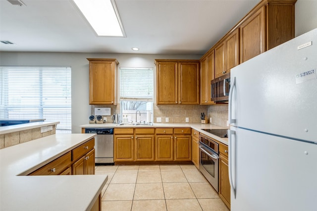 11398 Pear Ridge Dr, Frisco, TX 75035 - kitchen with appliances with stainless steel finishes, tasteful backsplash, light countertops, brown cabinets, and recessed lighting