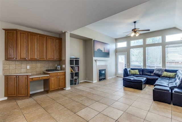 11398 Pear Ridge Dr, Frisco, TX 75035 - living area featuring light tile patterned floors, a ceiling fan, a tiled fireplace, and built in desk