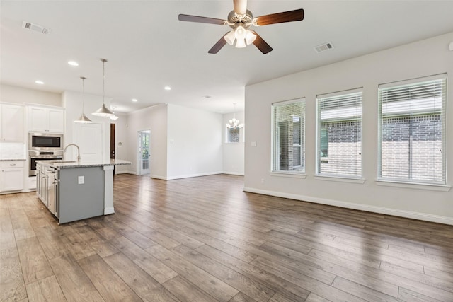 905 Plaza Ln, Argyle, TX 76226 - kitchen featuring stainless steel appliances, open floor plan, white cabinets, a center island with sink, and ceiling fan