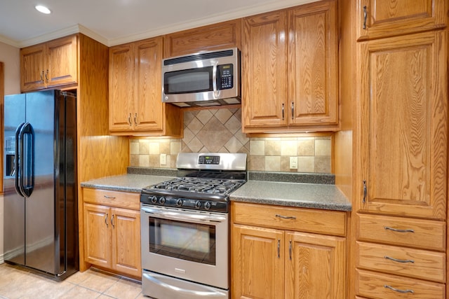 2086 Breezywood Dr, Flower Mound, TX 75022 - kitchen with appliances with stainless steel finishes, decorative backsplash, light tile patterned flooring, brown cabinets, and crown molding
