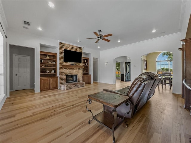 10353 W Dublin Dr, Forney, TX 75126 - living area with arched walkways, a ceiling fan, crown molding, a fireplace, and light wood-style floors