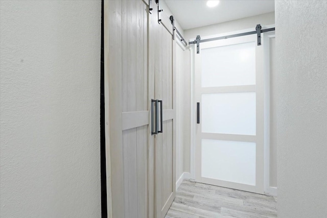 900 Amy Way, Bonham, TX 75418 - corridor featuring a barn door, wood finished floors, and a textured wall