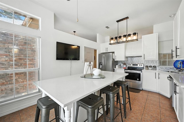8311 Paxson Trl, Dallas, TX 75249 - kitchen featuring stainless steel appliances, light tile patterned floors, backsplash, a center island, and a breakfast bar area