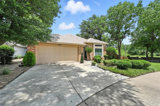 8311 Paxson Trl, Dallas, TX 75249 - view of front facade with concrete driveway, an attached garage, and stone siding