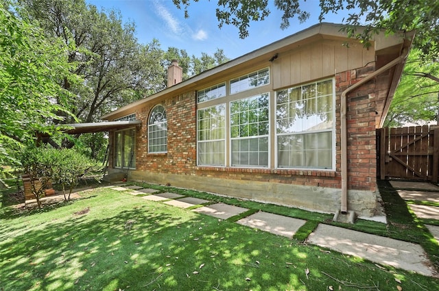 8311 Paxson Trl, Dallas, TX 75249 - view of side of home with brick siding, a chimney, and a gate