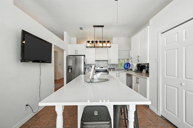 8311 Paxson Trl, Dallas, TX 75249 - kitchen featuring stainless steel appliances, a kitchen island, white cabinetry, light countertops, and a kitchen breakfast bar