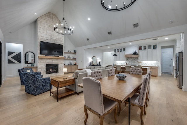 11405 Antler Ridge Way, Argyle, TX 76226 - dining room featuring a chandelier, high vaulted ceiling, a fireplace, and light wood-style flooring