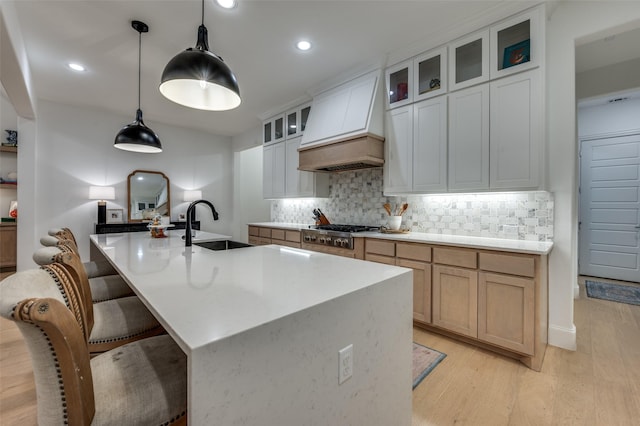 11405 Antler Ridge Way, Argyle, TX 76226 - kitchen with premium range hood, stainless steel gas stovetop, light wood-type flooring, tasteful backsplash, and an island with sink