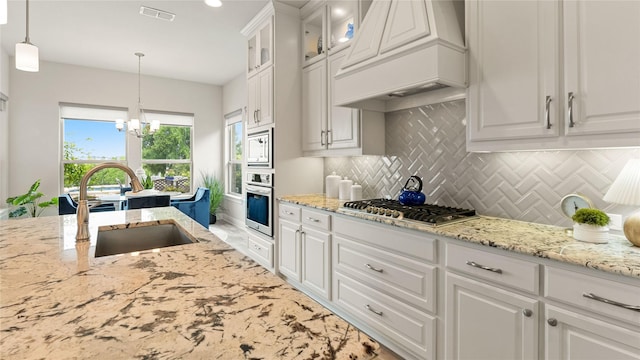 2809 Burgundy Trl, Rowlett, TX 75088 - kitchen with stainless steel appliances, premium range hood, white cabinetry, a chandelier, and light stone countertops