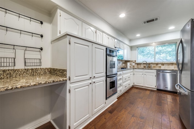 710 Northridge St, Denton, TX 76201 - kitchen featuring stainless steel appliances, dark wood-type flooring, light stone counters, backsplash, and white cabinets