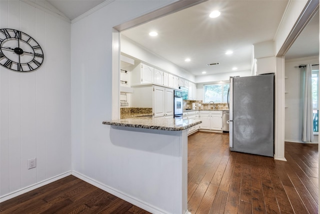710 Northridge St, Denton, TX 76201 - kitchen featuring stainless steel appliances, dark wood-style flooring, a peninsula, white cabinetry, and ornamental molding