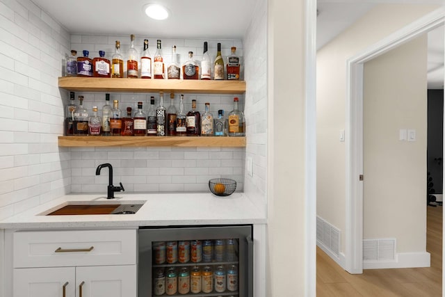 6207 Crested Butte Dr, Dallas, TX 75252 - indoor wet bar with decorative backsplash, light wood-style flooring, and beverage cooler