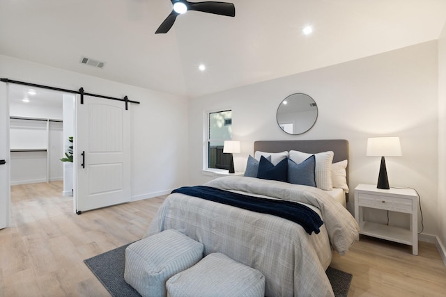 2605 S Glenbrook Dr, Garland, TX 75041 - bedroom with vaulted ceiling, a barn door, light wood-style flooring, a ceiling fan, and a spacious closet