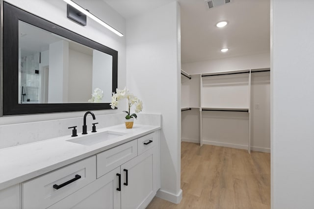 2605 S Glenbrook Dr, Garland, TX 75041 - bathroom featuring vanity, a spacious closet, and wood finished floors