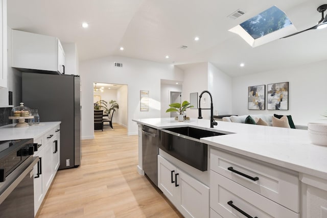 2605 S Glenbrook Dr, Garland, TX 75041 - kitchen with appliances with stainless steel finishes, vaulted ceiling, a skylight, light wood finished floors, and white cabinets