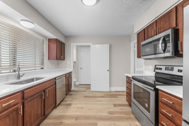 1124 Janell Dr, Irving, TX 75062 - kitchen featuring stainless steel appliances, light wood-style flooring, a textured ceiling, and light countertops
