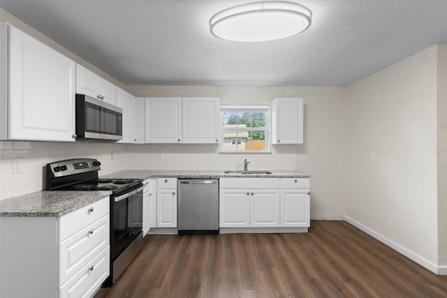 431 W Texas St, Denison, TX 75020 - kitchen with appliances with stainless steel finishes, tasteful backsplash, light stone countertops, dark wood-style flooring, and white cabinetry
