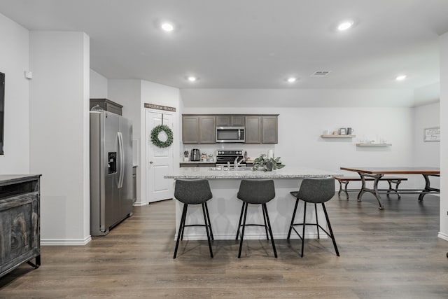 3216 Everly Dr, Fate, TX 75189 - kitchen featuring appliances with stainless steel finishes, a center island with sink, a kitchen bar, recessed lighting, and dark wood-style floors