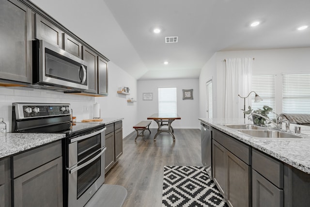 3216 Everly Dr, Fate, TX 75189 - kitchen with appliances with stainless steel finishes, wood finished floors, decorative backsplash, recessed lighting, and light stone countertops