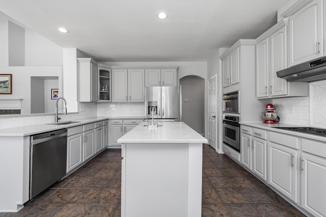 3912 Appleton Ln, Flower Mound, TX 75022 - kitchen with stainless steel appliances, arched walkways, under cabinet range hood, dark stone finish floors, and recessed lighting