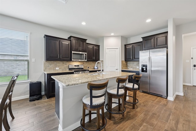 1083 Admiral Dr, Azle, TX 76020 - kitchen featuring stainless steel appliances, wood finished floors, tasteful backsplash, an island with sink, and light stone countertops