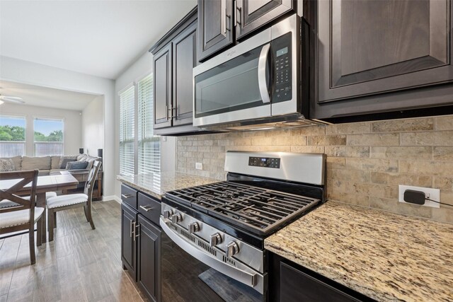 1083 Admiral Dr, Azle, TX 76020 - kitchen featuring appliances with stainless steel finishes, open floor plan, light stone counters, decorative backsplash, and light wood finished floors