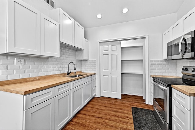 231 Juniper Dr, Pottsboro, TX 75076 - kitchen with appliances with stainless steel finishes, wood counters, tasteful backsplash, dark wood-type flooring, and white cabinetry