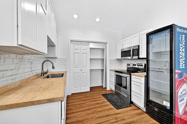 231 Juniper Dr, Pottsboro, TX 75076 - kitchen with appliances with stainless steel finishes, butcher block counters, white cabinets, decorative backsplash, and light wood-style flooring