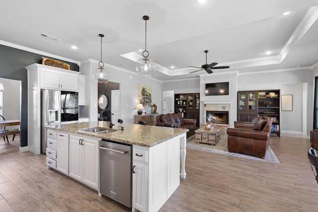 301 Aviara Ct, Poolville, TX 76487 - kitchen with stainless steel dishwasher, refrigerator with ice dispenser, a ceiling fan, a warm lit fireplace, and ornamental molding