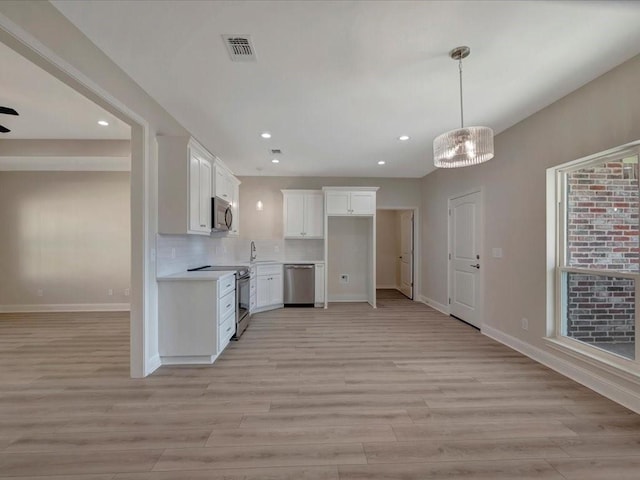 108 Saddle Brook Dr, Lufkin, TX 75904 - kitchen with stainless steel appliances, light wood-style flooring, recessed lighting, white cabinets, and light countertops