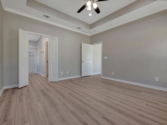 108 Saddle Brook Dr, Lufkin, TX 75904 - unfurnished bedroom with a tray ceiling, light wood finished floors, a walk in closet, crown molding, and a ceiling fan