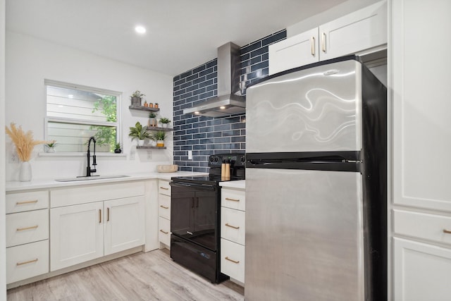 3005 Pate Dr, Fort Worth, TX 76105 - kitchen featuring freestanding refrigerator, black electric range oven, wall chimney range hood, tasteful backsplash, and white cabinetry