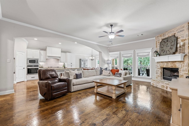 301 Prairie Oak Ct, Burleson, TX 76028 - living area with a ceiling fan, dark wood finished floors, a fireplace, arched walkways, and ornamental molding