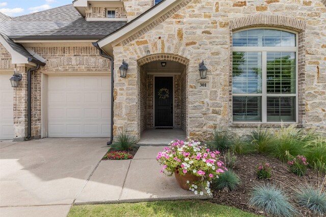 301 Prairie Oak Ct, Burleson, TX 76028 - view of exterior entry with a garage, stone siding, driveway, and roof with shingles